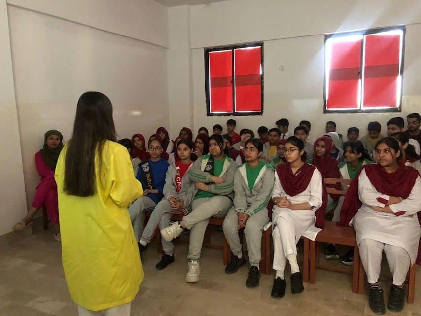 Lalain in yellow speaking to a room of seated students
