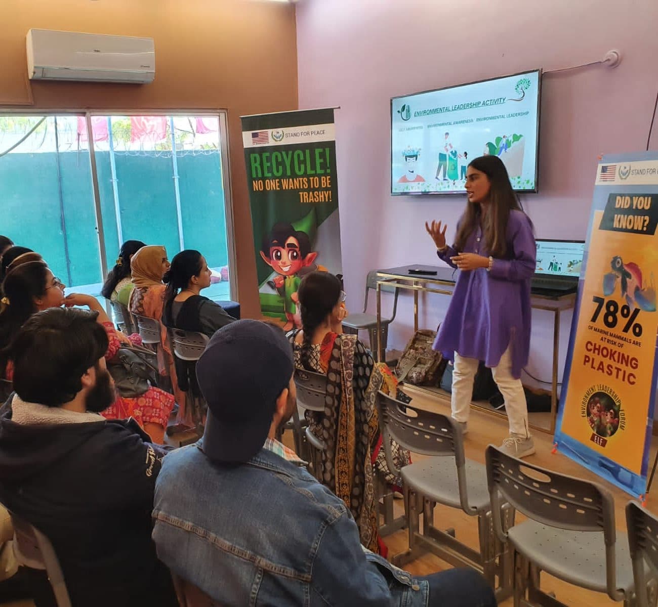 Lalain teaching a climate workshop beside recycling and plastic pollution banners