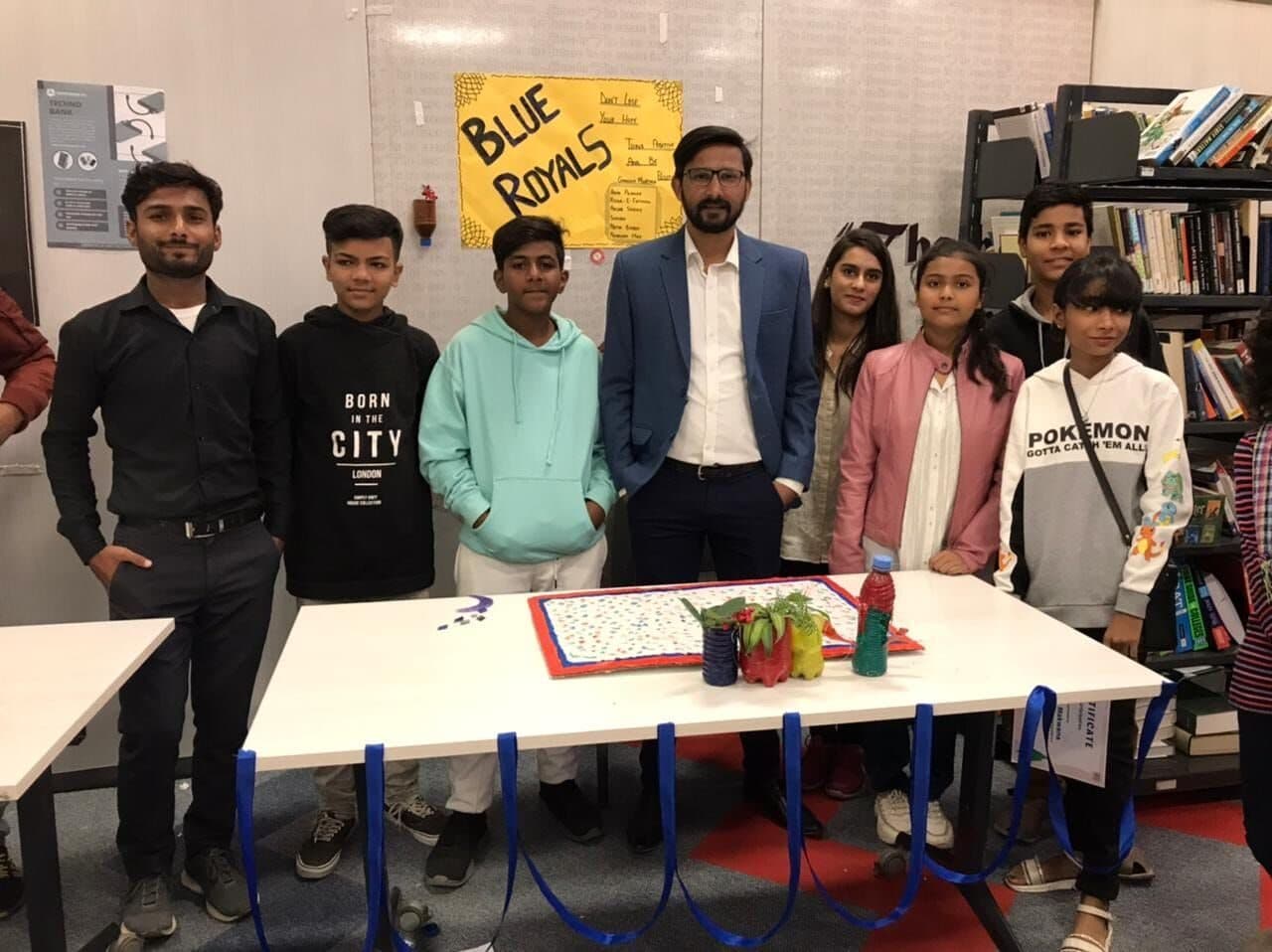 A team of campers standing behind the product they built, with Lalain and the other mentors