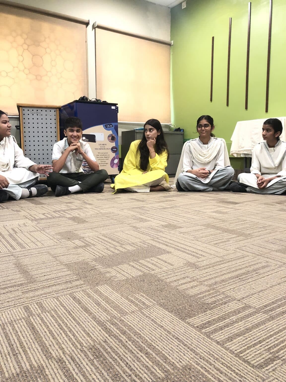 Students sitting in a circle on the carpet during a dialogue session