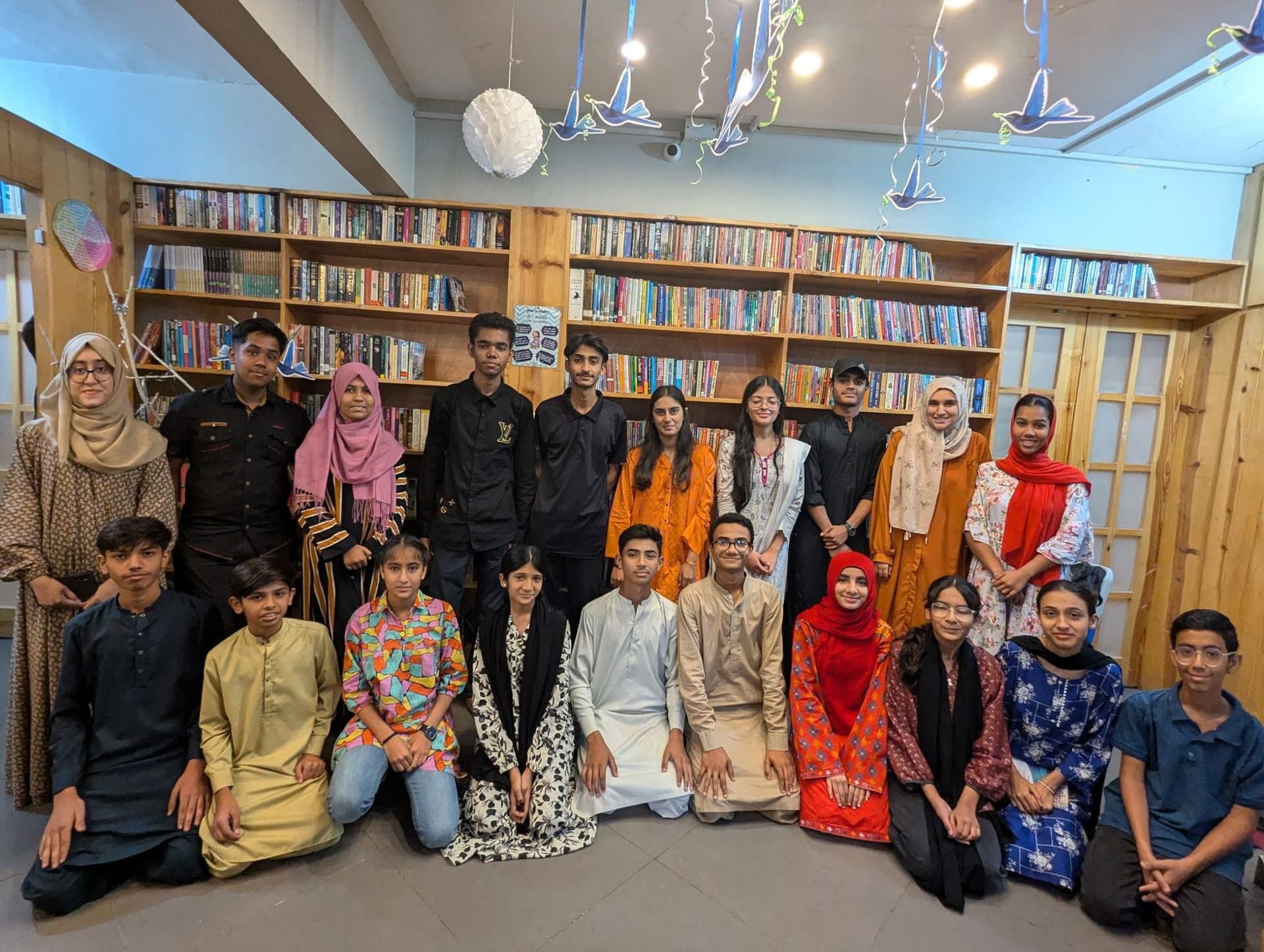 A group of young participants and facilitators posing in a library