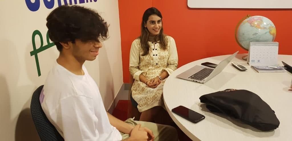 Lalain talking with one teenager across a table